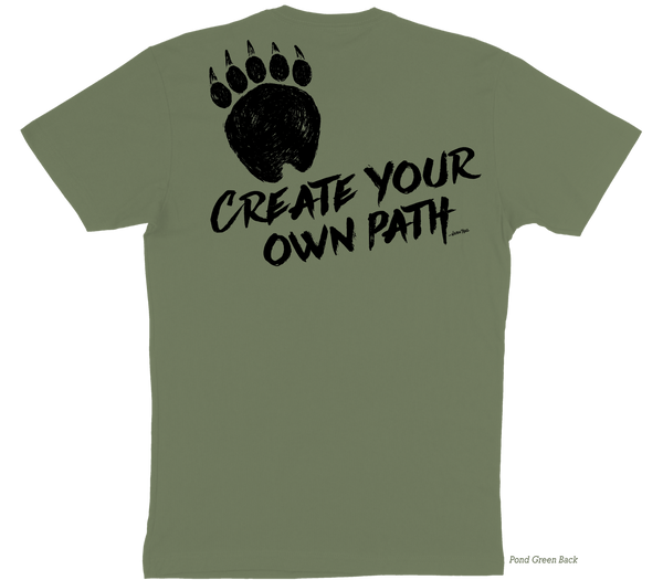 A muted green t-shirt back image containing a graphic of a grizzly bear paw on the top of the left side of the shirt with the slogan "Create Your Own Path Wilden Trail" underneath at an angle.