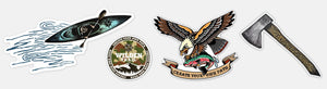 This image features four separate sticker designs. The first shows a man paddling a kayak. The second is a round sticker with a camouflage pattern. The third displays an eagle carrying a trout with a banner that reads “Create Your Own Path.” The fourth design shows an axe with the logo positioned in the upper right corner.